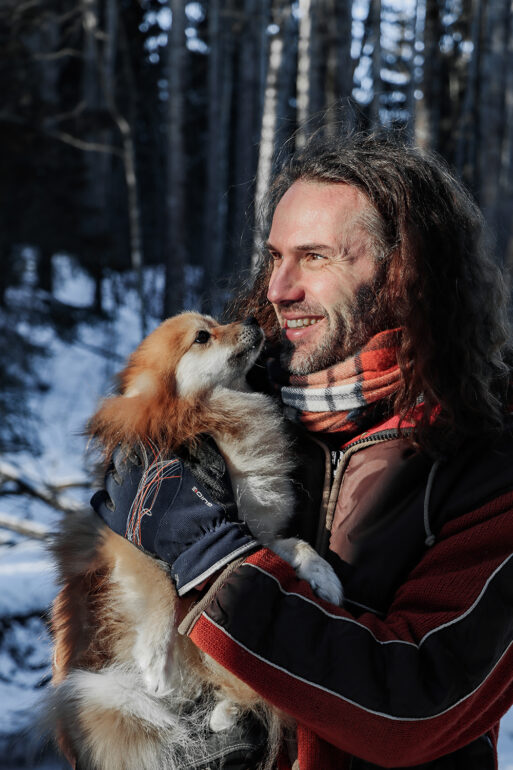 Michel talvisessa metsässä koira sylissään.