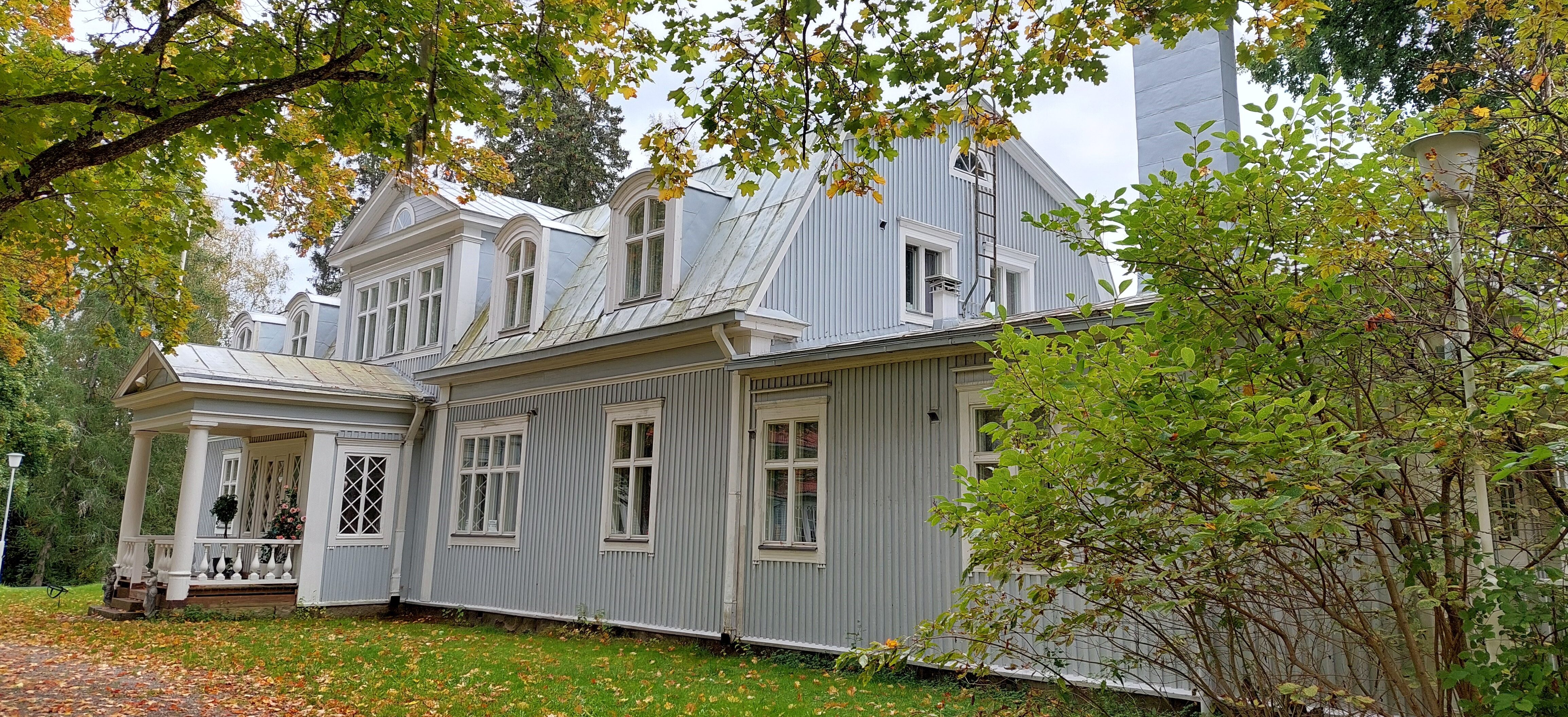Vaalea kartanorakennus syksyisellä pihalla.