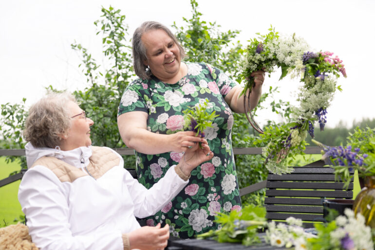 Naisia tekemässä kesäisiä kukkakimppuja.