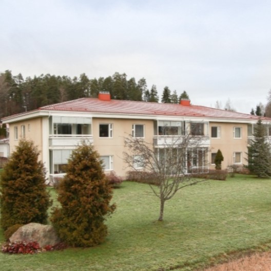 Vaalea luhtitalo puistoisella pihalla.