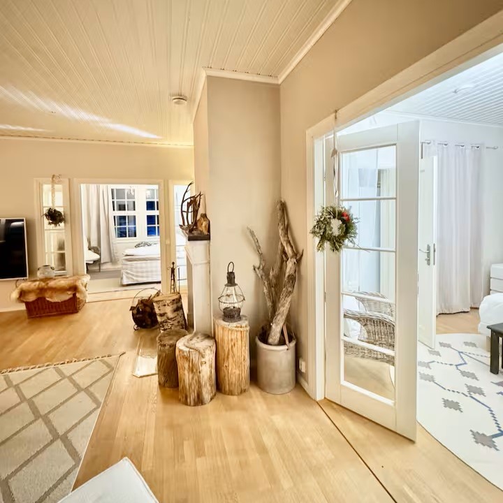 Kotoisa olohuone, vasemmassa reunassa ovet auki makuuhuoneeseen.