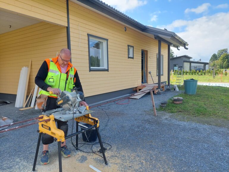 Mies sahaa omakotityömaalla.
