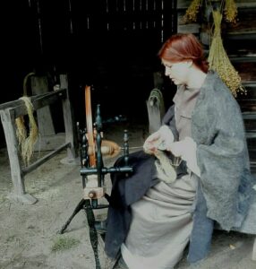 Crofter woman is making yarn using the spinning wheel at Laurinmäki Crofter's museum