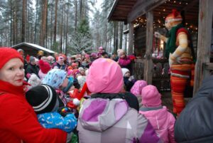 Esiintyjä Katti Matikainen tervehtii runsasta lasten yleisöä Vähä-Kurjen torpan kuistilla Laurinmäen joulunavauksessa.