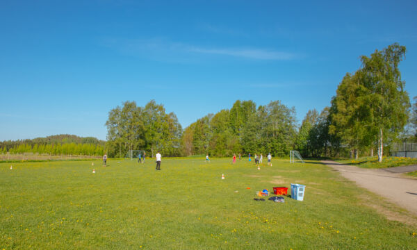 Nurmikenttä, jossa lapsia pelaamassa.