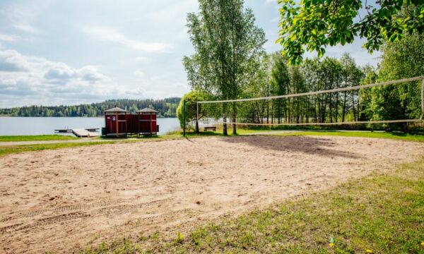 Lentopalloverkko Valajärven hiekkarannalla, taustalla järvimaisema.