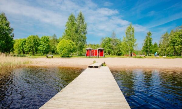 Tietyn uimaranta Tervakoskella kesäpäivänä laiturilta kuvattuna. Rannalla punainen pukukoppi.