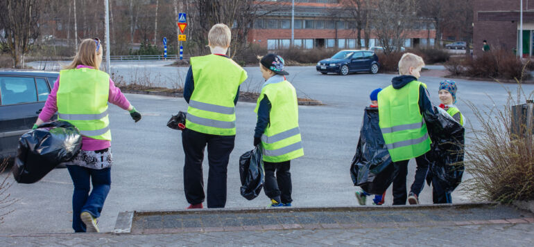 Nuoria Kui Siistii! talkoissa menossa keräämään roskia jätesäkkien kansssa huomioliivit päällä.