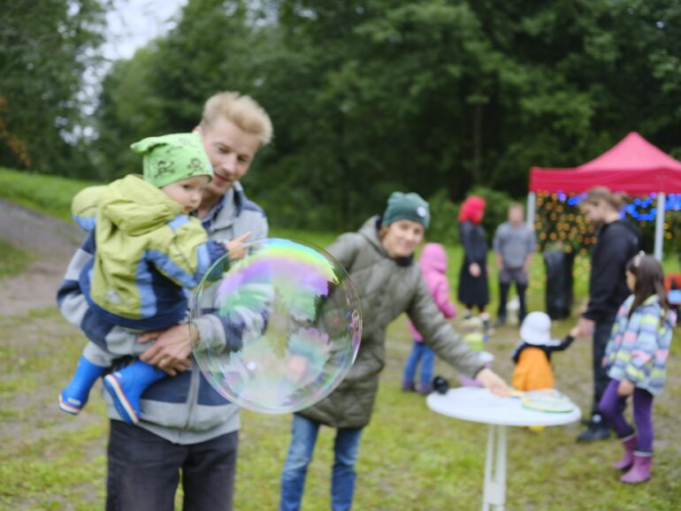 Cha và con tự hỏi bong bóng xà phòng lớn, mẹ trong nền.