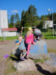 Lapset leikkimässä ison kiven päällä päiväkodin pihassa.