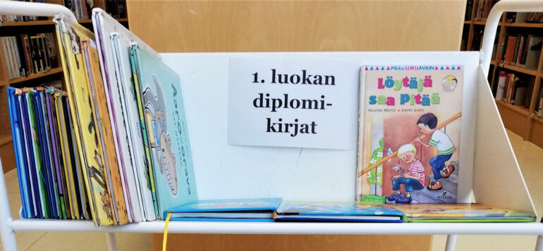1. luokan lukudiplomikirjoja kirjakärryssä.