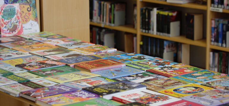 Lasten kirjoja aseteltuna kirjaston pöydälle vierekkäin.