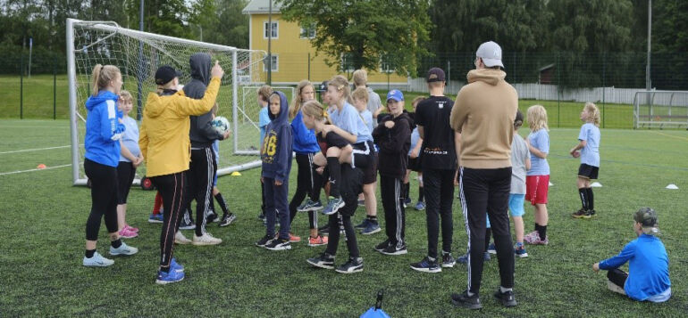 SC Urbansin kesäleirillä lapset ja ohjaajat jalkapallokentällä kerääntyneenä maalin taakse.