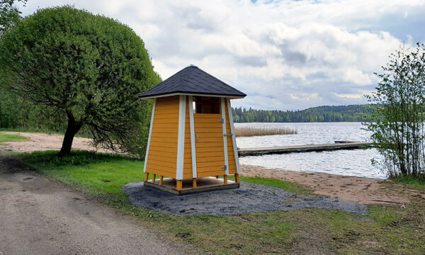 Tietyn uimarannan keltainen pukukoppi sekä pitkä laituri.