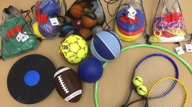 Liikuntavälinelainaamon välineitä, mm. tasapainolauta, amerikkalainen jalkapallon, tennismailat ja hulavanne.