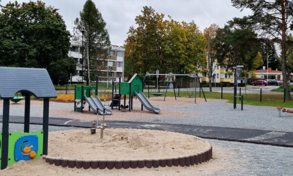 Kivimiehentien leikkipaikan leikkivälineitä, mm. hiekkalaatikko, kiipeilyliuku sekä keinut.
