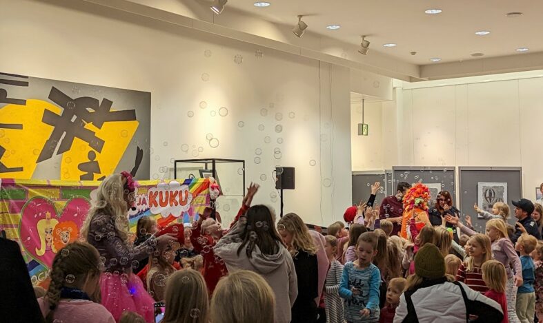 Lastenkonsertti kirjaston aulassa, jossa paljon lapsia, saippuakuplia ja esiintyjänä Mimi ja Kuku.