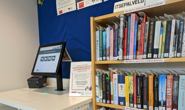 Lainausautomaatti ja varaushylly, jossa varattuja kirjoja.