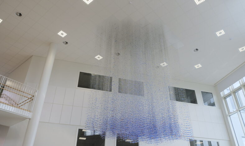 Lasihelmistä koostuva taideteos roikkuu katosta.