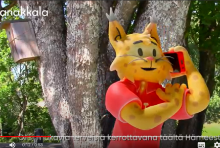 Kuntamaskotti puhuu kännykkään.