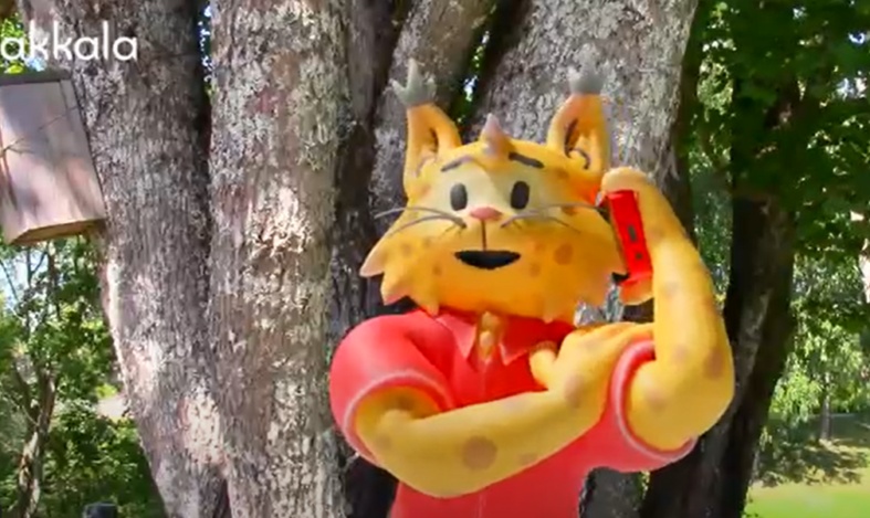 Kuntamaskotti, ilves puhuu puhelimessa, kuvakaappaus videosta.