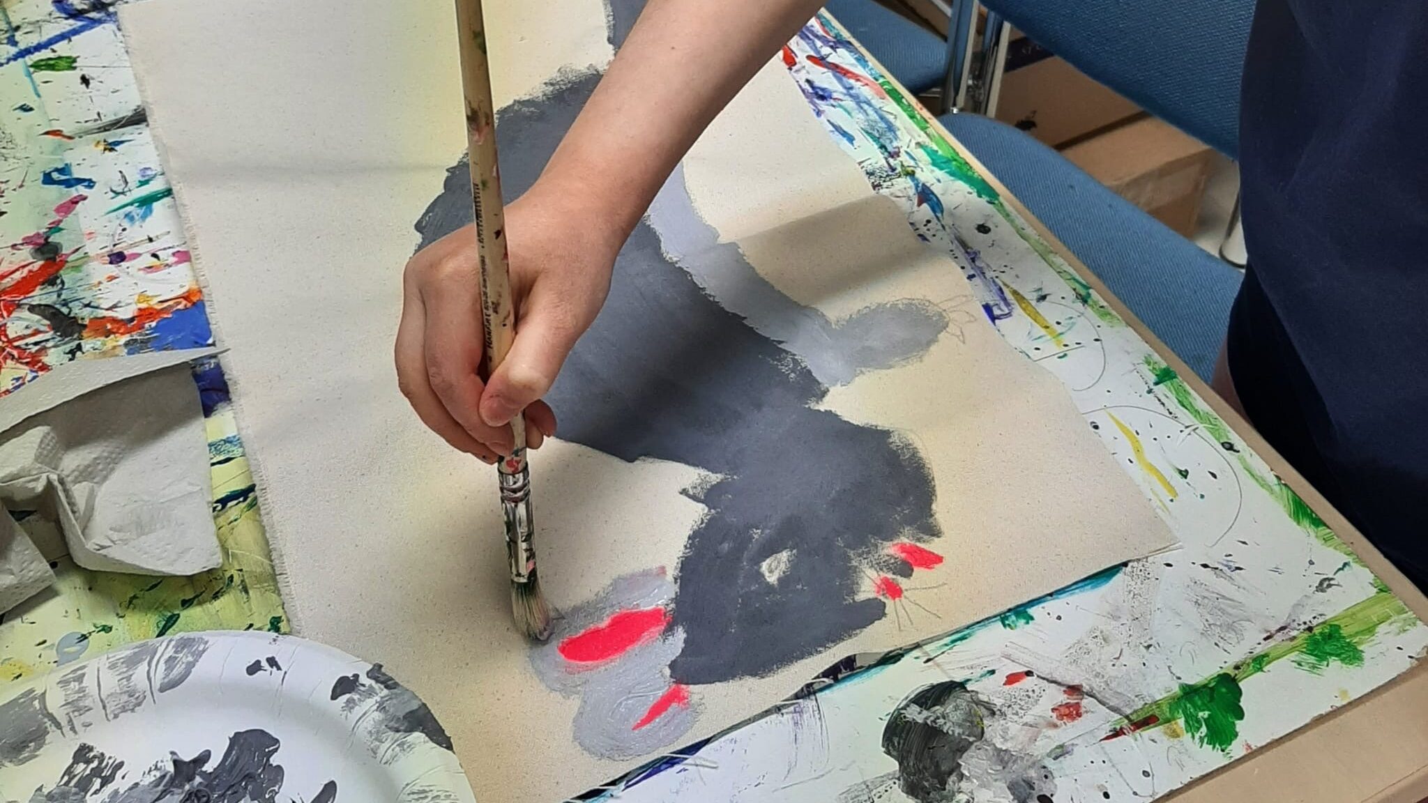 Lapsi maalaa harmaan rotan kuvaa paperille.