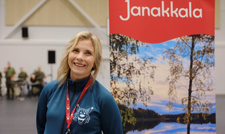 Liikuntapäällikkö messuilla Janakkala-mainoksen edessä.