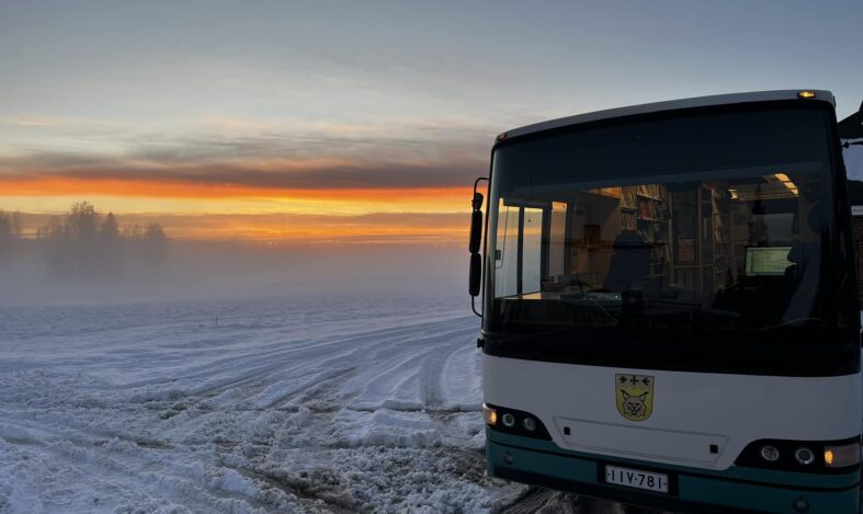 Janakkalan kirjastoauto auringonlaskussa talvisessa peltomaisemassa.