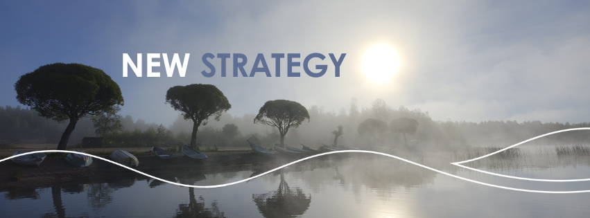 Foggy view of Ahilammi beach. Sun shines through the fog, there are trees and rowing boats on the shore.