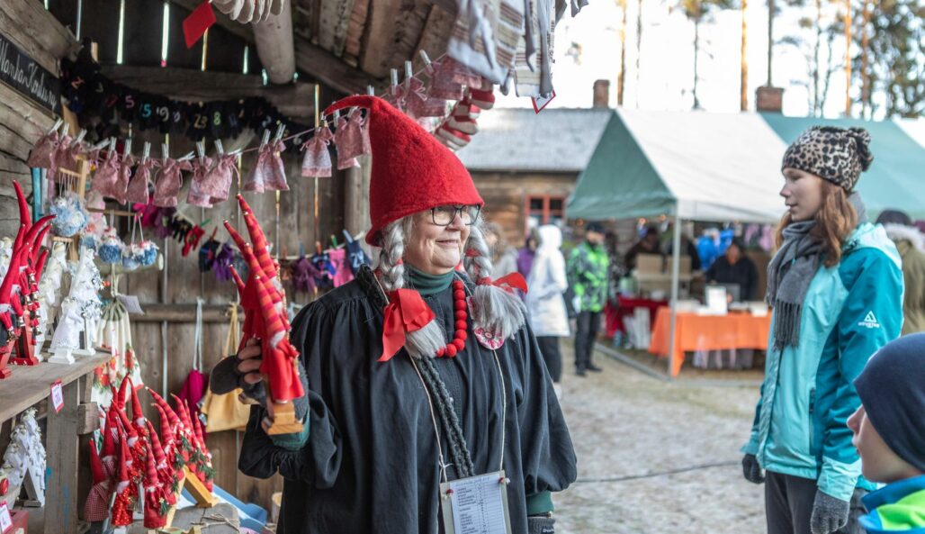 A vendor with a Christmas hat showcasing their elves for customers.