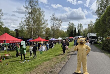 Kunnan maskotti The Ilves seisoo jalkakäytävällä. Taustalla tapahtumatelttoja.