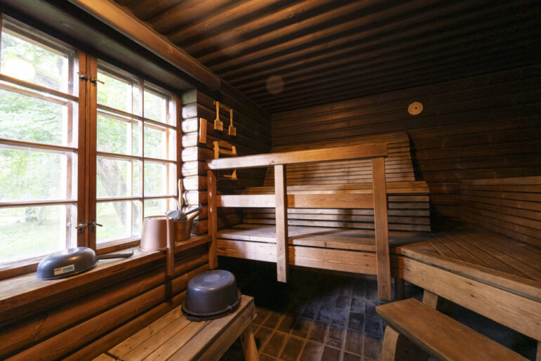 Sauna, jossa lauteet vasemmassa reunassa ja kuvan keskellä. Oikeassa reunassa suuri ristikkoikkuna.